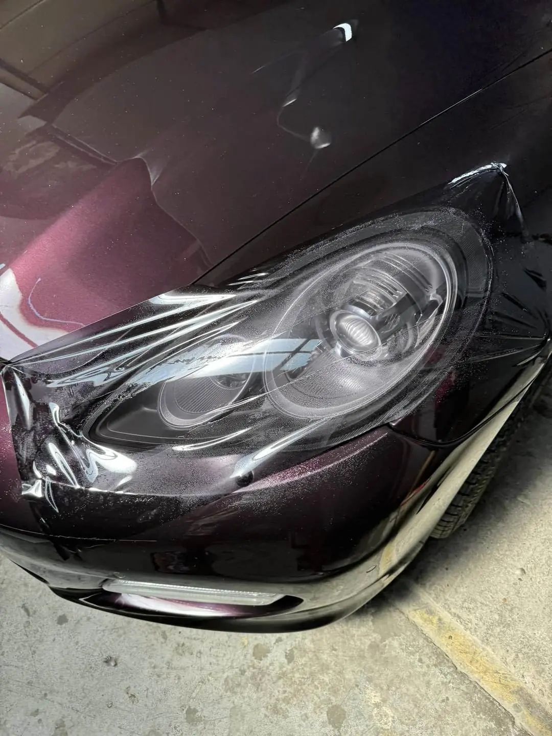Detaliu lucru — folie de protecție aplicată pe far Porsche